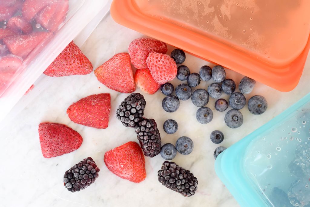 Vibrant, frost-free strawberries and blueberries inside a hermetic bag for freezing, placed in a wire freezer basket