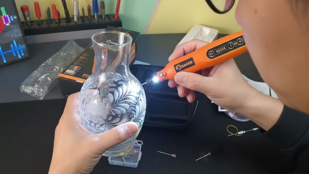 Person engraving detailed pattern on glass using diamond bit with LED light
